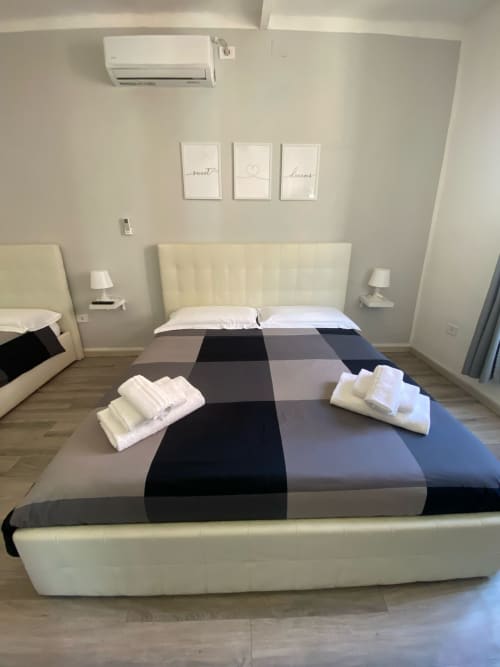 Modern bedroom at Newhouse Bari with cream upholstered bed, striped comforter, and white towels