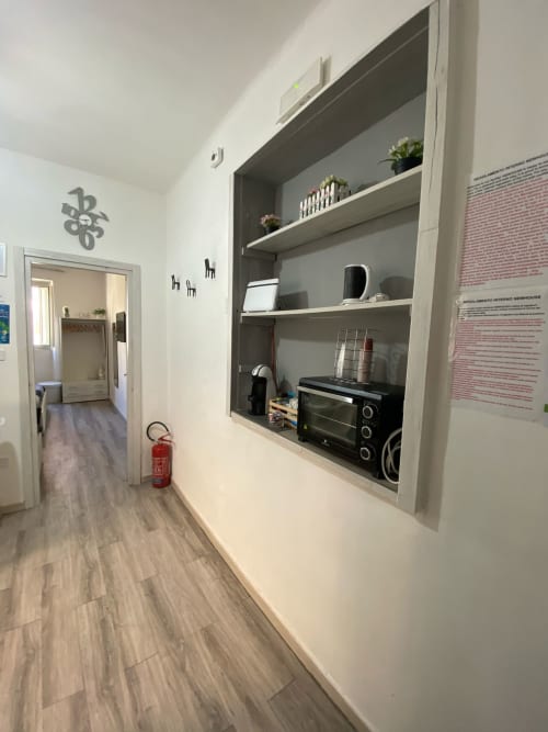 Corridoio moderno dell'appartamento Newhouse a Bari con scaffalature integrate, angolo cottura e pavimentazione in legno