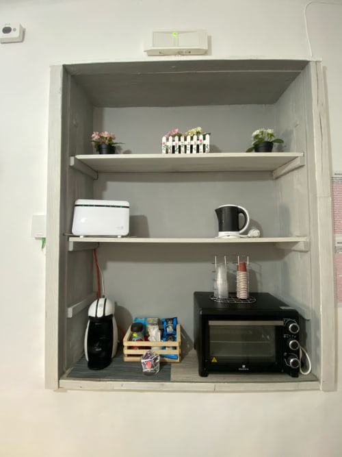Scaffale aperto nell'appartamento Newhouse Bari con piante in vaso, utensili da cucina, forno tostapane e caffettiera