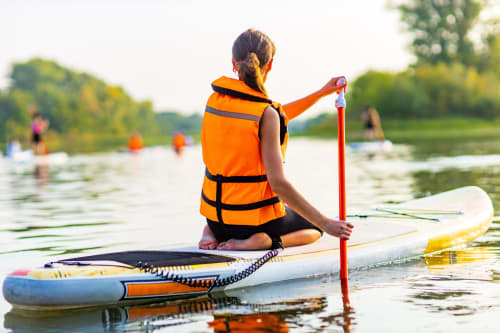 woman sitting on an inflatable sup board with paddle. Healthy recreation on a river and water sports