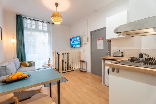 Modern studio apartment in Bordeaux with open-plan kitchen, living area, crib, and city views through large windows