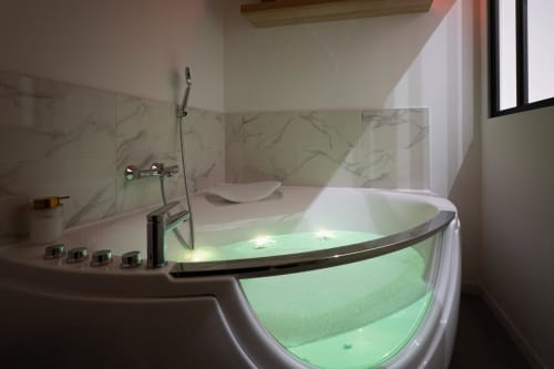 Luxurious Jacuzzi bathtub with green ambient lighting in modern bathroom at Wellkhome Bordeaux apartment