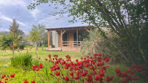 Villa moderne en bois avec fleurs rouges dans le jardin de Le Maquis Plage, Corse