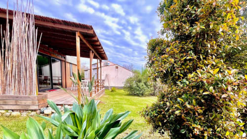 Mobil-home Le Maquis Plage avec terrasse en bois, pelouse verdoyante et plantes méditerranéennes à Poggio-Mezzana