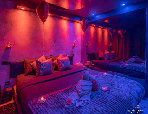 Appartement spa luxueux à L'Insolite Toulouse avec éclairage rose néon et bleu, lits multiples, pétales de rose, ambiance romantique