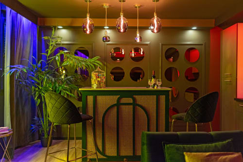 Lounge contemporain du L'Insolite Spa Privatif à Toulouse avec luminaires suspendus, bar vert, accents rouges et mobilier design.