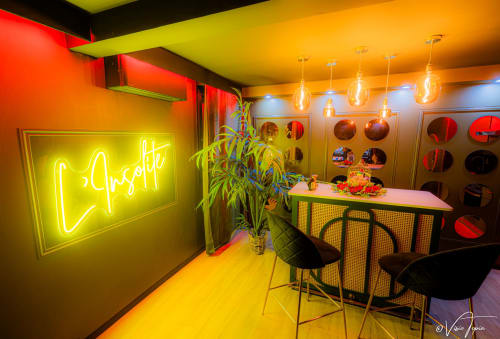 Espace bar vibrant aux néons à L'Insolite Spa Privatif à Toulouse, enseigne jaune, luminaires suspendus et mobilier moderne