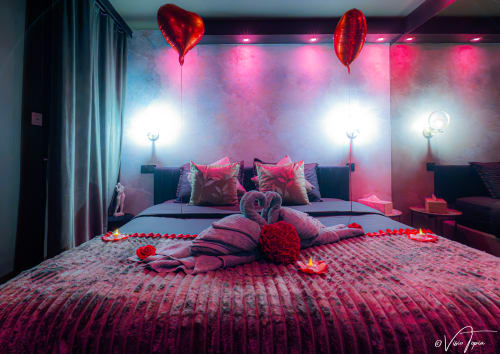 Chambre romantique à L'Insolite Spa Privatif Toulouse avec ballons cœurs rouges, pétales de rose et ambiance rose