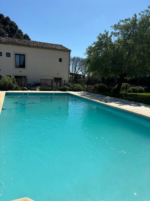 Turquoise swimming pool with villa and gardens at La Conciergerie De Franck in Boissieres