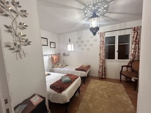 Chambre twin dans un appartement à Arles avec lits blancs, suspension marocaine et vue sur le jardin par les fenêtres aux volets bordeaux