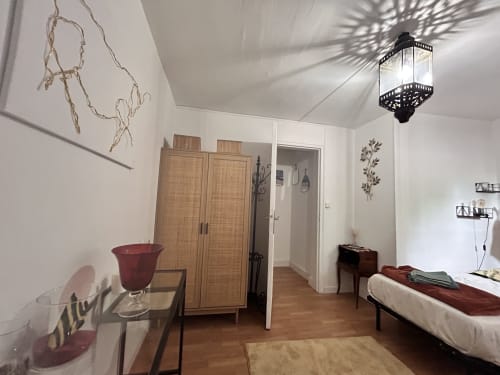 Chambre moderne à l'appartement Conciergerie Maurin à Arles avec penderie en bois, accents rouges et éclairage suspendu