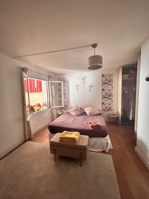 Chambre spacieuse dans un appartement d'Arles avec lit queen-size, parquet, fenêtre avec vue sur jardin et éclairage suspendu
