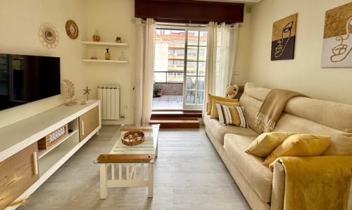 Luminosa sala de estar del apartamento Luceira en Baiona con sofá beige, TV y balcón con vistas al mar