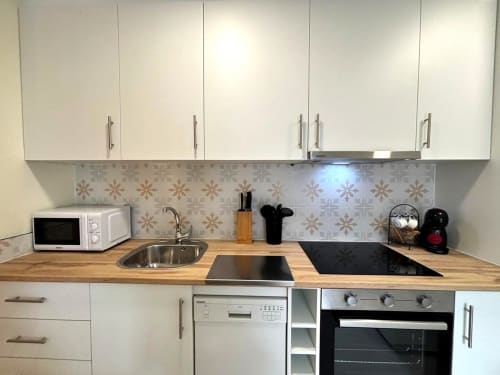 Cocina moderna en apartamento Holibai, Baiona con armarios blancos, encimera de madera, electrodomésticos de acero inoxidable y diseño estampado