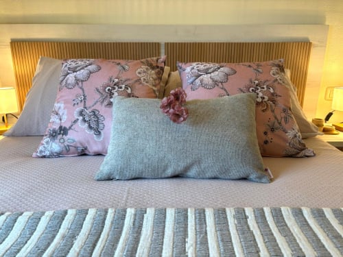 Dormitorio del apartamento Luceira en Baiona con almohadas florales, vistas al mar y ropa de cama a rayas