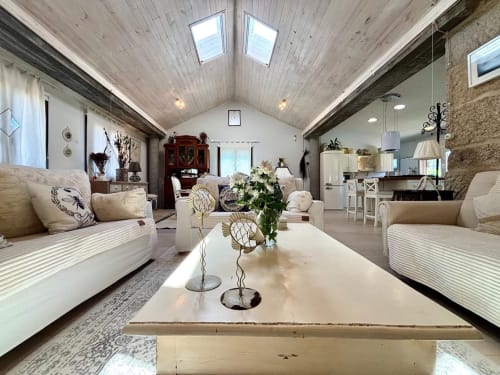 Amplia sala de estar en Casa Celso cerca de Baiona con sofás crema, techo abovedado, tragaluz, chimenea y jardín