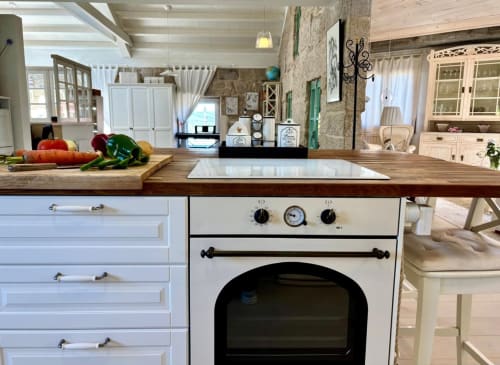 Cocina de casa de campo moderna en Casa Celso de Baiona con encimeras de madera, muebles blancos y horno de estilo vintage