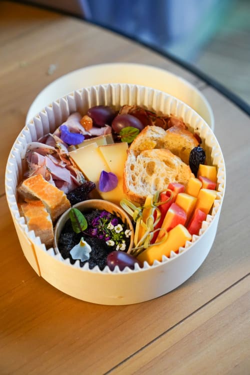 Plateau gastronomique de charcuterie et fromages avec pain frais et fleurs comestibles aux Cabanes et lodges du Belvédère, Serrières-sur-Ain