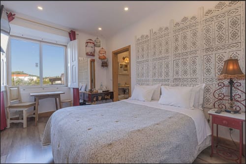 Bright bedroom at Ninho Saloio hotel in Venda do Pinheiro with queen bed, wooden desk, patterned headboard and window view.