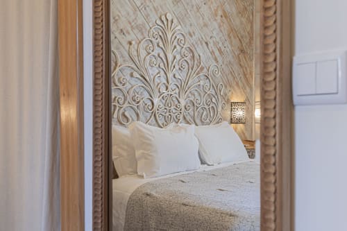 Ninho Saloio hotel standard room with ornate headboard, white pillows, beige bedding, and decorative wall lamp