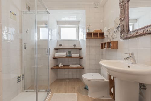 Modern bathroom with walk-in shower, sink, toilet, and wooden shelving at Ninho Saloio hotel in Venda do Pinheiro