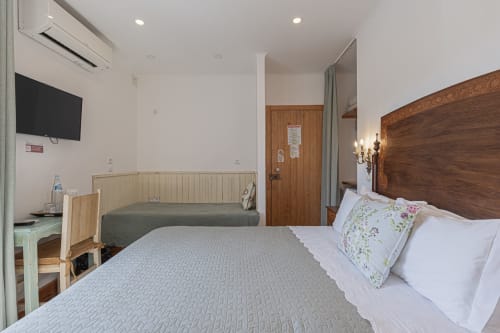 Premium hotel room at Ninho Saloio with double bed, wooden headboard, TV, and traditional Portuguese décor in Venda do