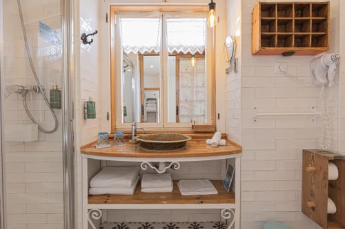 Luxury bathroom vanity with wooden countertop, vessel sink, mirror, and shower at Ninho Saloio in Venda do Pinheiro