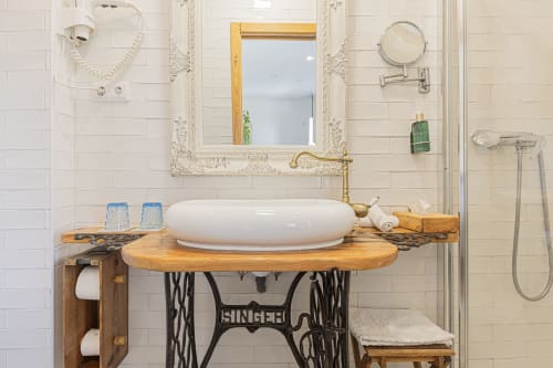 Luxurious bathroom vanity with vessel sink on wooden base at Ninho Saloio, featuring antique mirror and premium fixtures