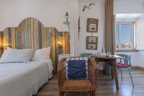 Seagull Studio at Ninho Saloio featuring a colorful wooden headboard bed, wicker chair, wooden desk, and lake views in Venda