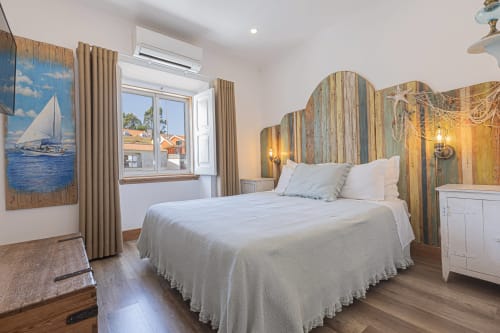 Seagull Studio bedroom at Ninho Saloio with wooden headboard, white linens, sailboat artwork, and lake view at Venda do