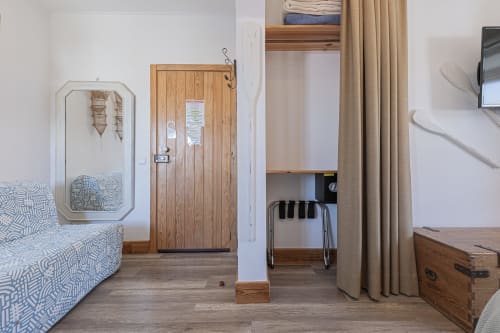 Seagull Studio bedroom at Ninho Saloio with patterned bed, wooden wardrobe, desk area, and garden view in Venda do Pinheiro