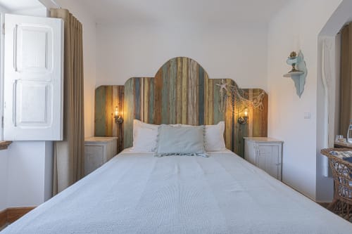 Seagull Studio bedroom at Ninho Saloio with rustic wooden headboard, white bedding, and nautical decor