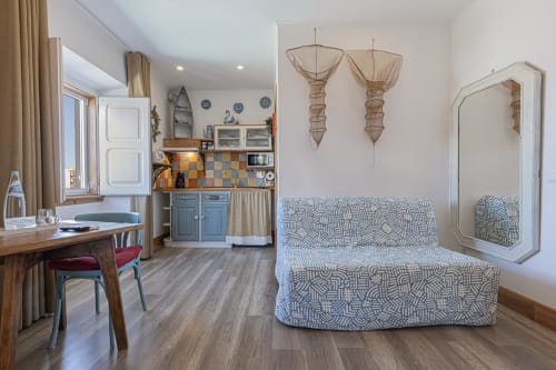 Seagull Studio at Ninho Saloio with patterned sofa, desk, kitchenette, decorative fishing nets, and mirror in Venda do