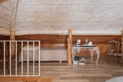 Rustic loft bedroom at Ninho Saloio with wooden beams, white metal bed frame, and wrought iron desk in Venda do Pinheiro.