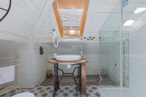 Rustic bathroom at Ninho Saloio with white vessel sink on vintage Singer sewing machine base, skylight, and glass shower
