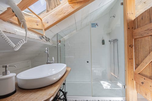 Modern bathroom with oval sink, glass shower enclosure, wooden beams and skylight at Ninho Saloio hotel in Venda do Pinheiro