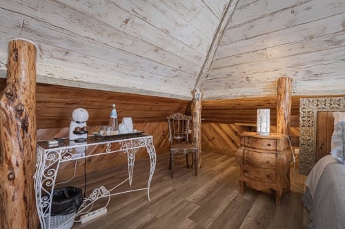 Rustic wooden bedroom at Ninho Saloio with exposed log beams, white ceiling, ornate desk, and hardwood floors in Venda do