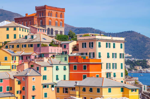 Edifici colorati della waterfront di Genova con montagne e mare blu, zona hotel Pellicceria Superiore