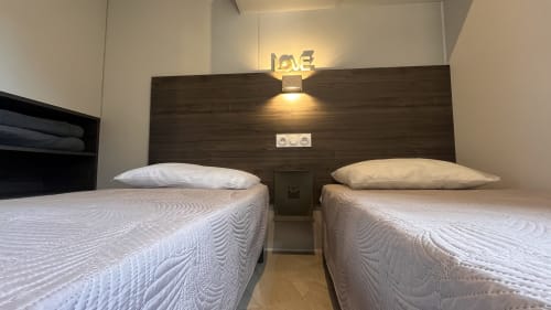 Chambre twin moderne de la villa Le Maquis Plage avec deux lits, tête de lit en bois sombre et éclairage d'ambiance à Poggio-Mezzana