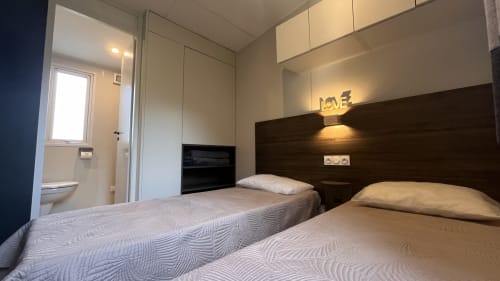 Lits jumeaux dans une chambre moderne de mobil-home au Maquis Plage, Poggio-Mezzana avec salle de bain privée et télévision écran plat