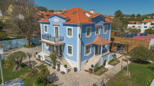 Villa azul e branca Ninho Saloio com telhado em barro em Venda do Pinheiro, Portugal, cercada por jardins verdejantes