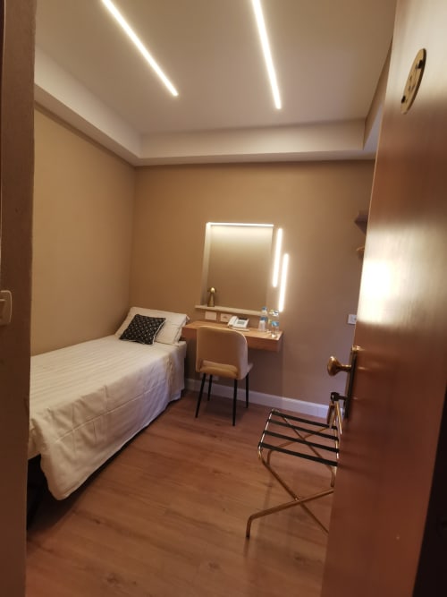 Camera singola moderna dell'Hotel Fiori Roma con letto, scrivania, specchio illuminato e pavimento in parquet