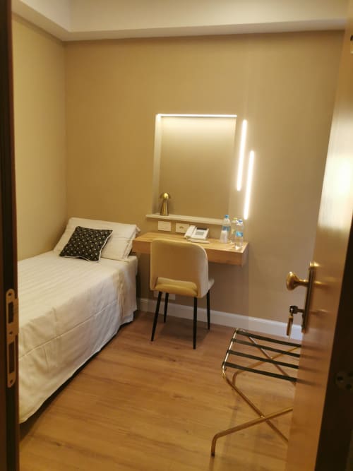 Camera singola moderna presso Hotel Fiori Roma con letto, scrivania, specchio illuminato, pavimento in legno e arredi eleganti