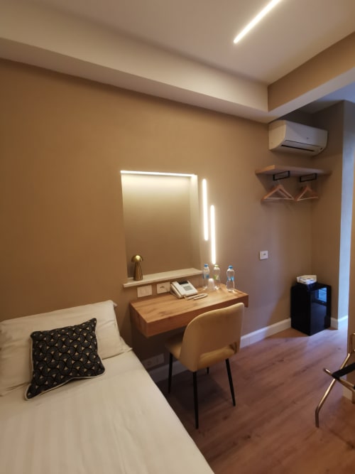 Camera moderna dell'Hotel Fiori a Roma con letto, scrivania con specchio illuminato, sedia in legno, climatizzatore e