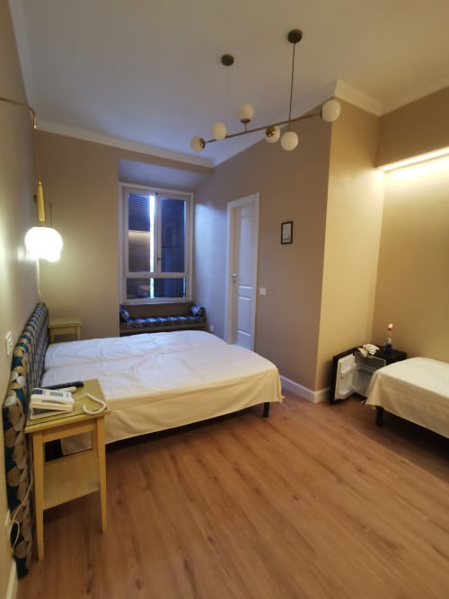 Camera matrimoniale deluxe all'Hotel Fiori di Roma con due letti, pavimentazione in legno, illuminazione a sospensione moderna e vista sulla città