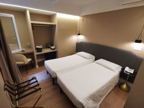 Camera doppia deluxe presso Hotel Fiori a Roma con due letti, scrivania, specchio trucco, illuminazione moderna e pavimenti in legno.