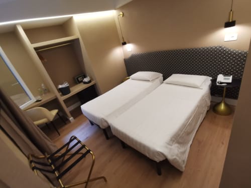Camera doppia deluxe all'Hotel Fiori Roma con due letti, testiera scura, pavimento in parquet, illuminazione moderna e spazio guardaroba.