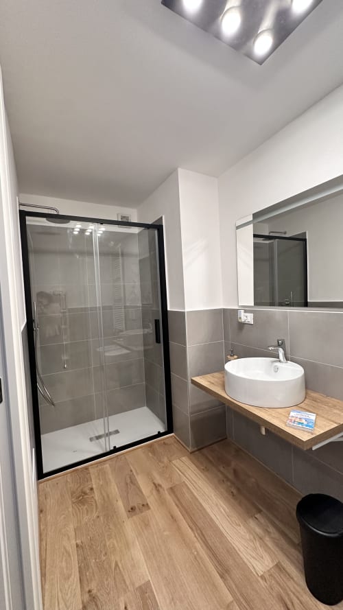 Bagno moderno dell'hotel Pellicceria Superior di Genova con cabina doccia, lavabo rotondo, mobile vanità in legno e scaldarancia