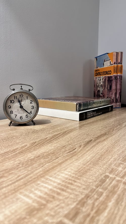 Sveglia vintage e libri su scrivania in legno presso l'hotel Pellicceria Superior a Genova