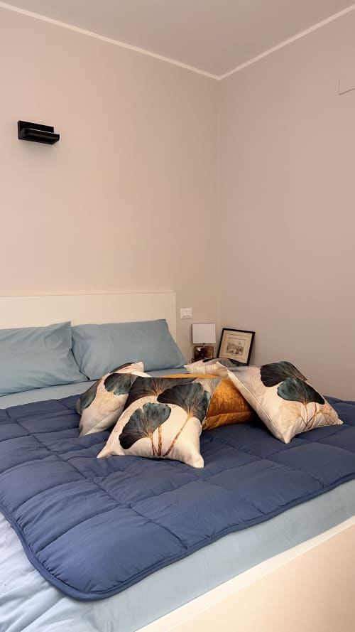 Camera moderna della Pellicceria Superior Genova con biancheria blu, cuscini decorativi floreali e unità AC a parete
